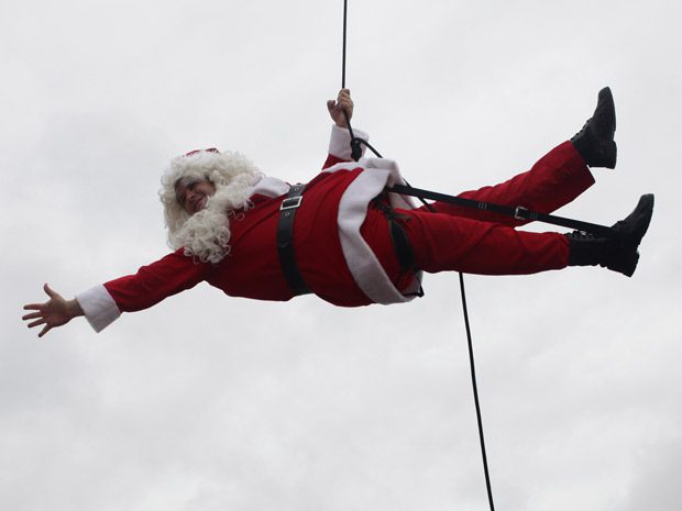 Le Père Noel est suspendu à une corde comme s'il faisait de l'accrobranche